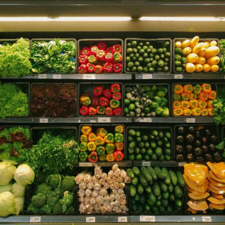 „Buntes Gemüse-Sortiment in einem Supermarktregal, darunter Paprika, Salat, Gurken, Brokkoli und Zucchini, frisch präsentiert.“
